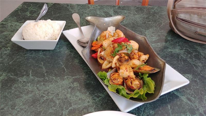 Grilled Thai beef slices on a hot plate with herbs and dipping sauce